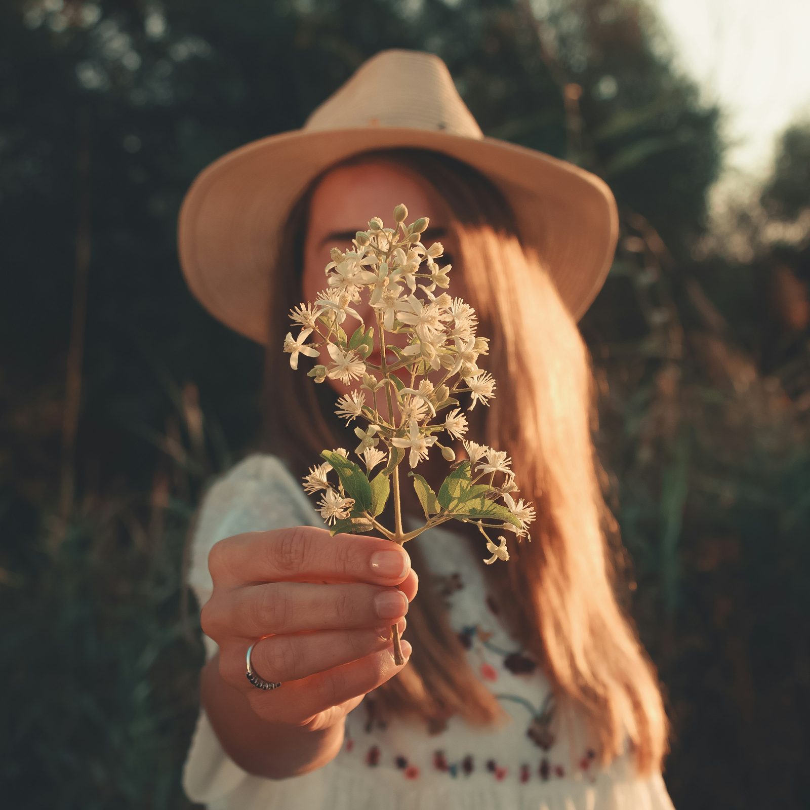 Femme au chapeau tenant des fleurs blanches